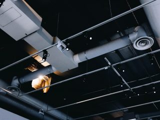 A low angle shot of a metal black ceiling with white ventilation pipes